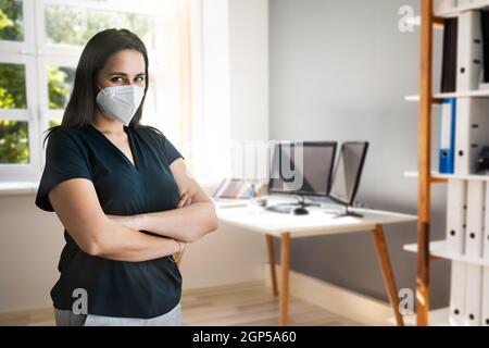 Donna presso la reception dell'ufficio in FFP2 Face Mask Foto Stock