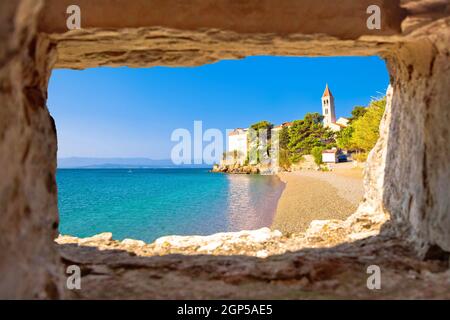 Monastero sulla spiaggia di ciottoli a Bol vista attraverso la finestra di pietra, isola di Brac, Dalmazia, Croazia Foto Stock