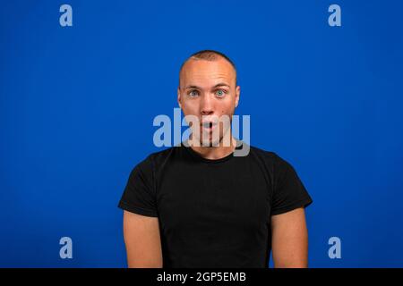 Foto di pazzo stupito giovane uomo a bocca aperta informazioni incredibile isolato su sfondo blu Foto Stock