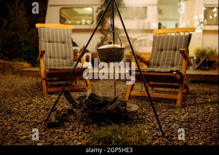 Pentola è sopra il fuoco, pic-nic in campeggio nella foresta, nessuno. Avventura estiva su camper, campeggio-auto su sfondo. Viaggiare con rimorchio, cucinare Foto Stock