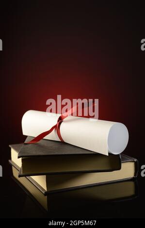 Un diploma in cima a un paio di libri mostra il successo di profitto degli studi scolastici. Foto Stock