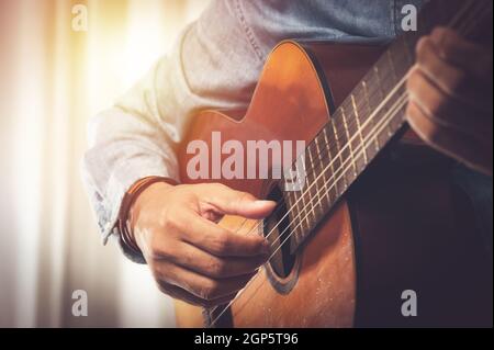 mano dell'uomo closeup che suona la sua vecchia chitarra classica. Foto Stock