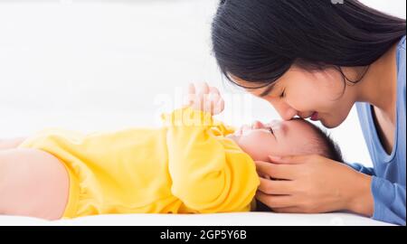 Ritratto di bella giovane madre asiatica baciando il suo neonato neonato in un letto bianco, la mamma ama il suo bambino, la sanità e medico e madre da Foto Stock