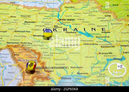 Bandiera nazionale Ucraina ha bloccato sulla mappa politica dell'Europa. Macro primo piano su un atlante del mondo colorato e sfocato con attenzione al paese capitale - Kiev Foto Stock