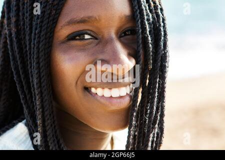 Primo piano su faccia esterna shot di esotico adolescente africano con braid.Girl sorridente e mostrando denti bianchi sani e perfetti.