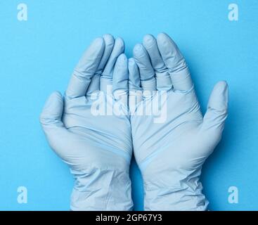 due mani femminili in guanti di lattice blu, palme da medico su sfondo blu, vista dall'alto Foto Stock