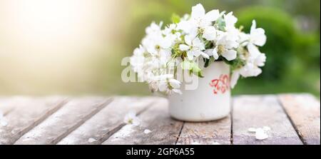 Vita morta con tazza e bouquet di rami con fiori di mela. Petali bianchi di alberi fioriti caduti su cemento Foto Stock