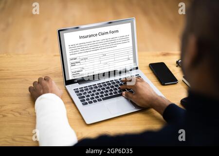 Copertura di risarcimento danni al lavoratore con braccio rotto. Utilizzo di un portatile Office Foto Stock