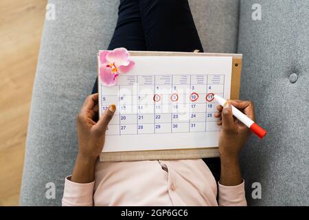 Donna africana che usa il ciclo mestruale o il calendario del periodo Foto Stock