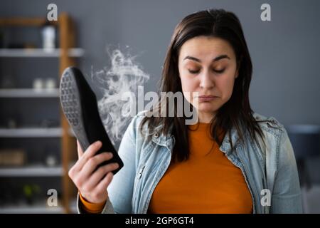 Donna che odora le scarpe Stinky. Piedi Sweat e Odor Foto Stock