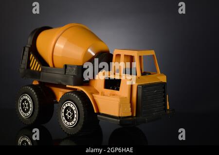 Un miscelatore di cemento giocattolo su uno sfondo sfumato scuro. Foto Stock
