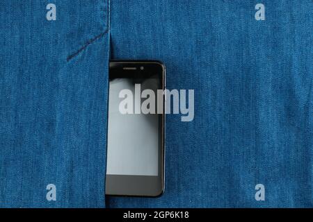 Parte di cellulare in tasca di jeans blu, vista dall'alto Foto Stock