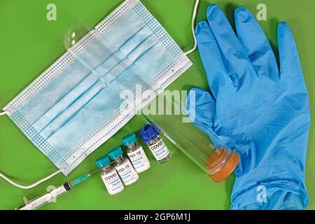 Flaconi di vaccini con coronavirus con siringa maschera facciale per provette e. guanto in ospedale pronto per l'uso Foto Stock