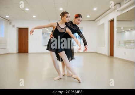 Coreografo lavora con la giovane ballerina in classe. Scuola di balletto, ballerini femminili in coreografia, ragazze che praticano la danza della grazia Foto Stock