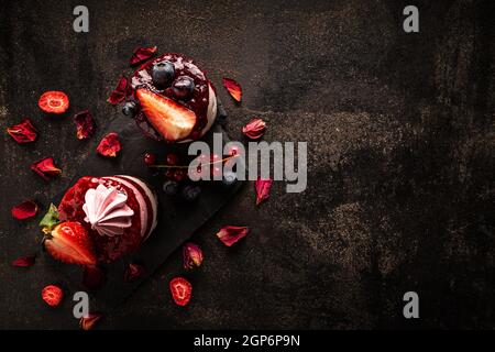 Mini cheesecake rotonda alla fragola su ardesia nera con spazio per il tuo testo Foto Stock