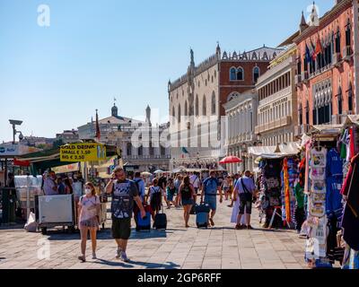 Turisti e bancarelle di fronte al Palazzo Ducale sul lungomare della Rive degli Schiavoni, Venezia, Veneto, Italia Foto Stock