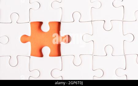 Vista dall'alto piatto di carta comune bianco jigsaw puzzle game texture incompleto o mancante pezzo, studio girato su sfondo arancione, quiz calcolo c Foto Stock