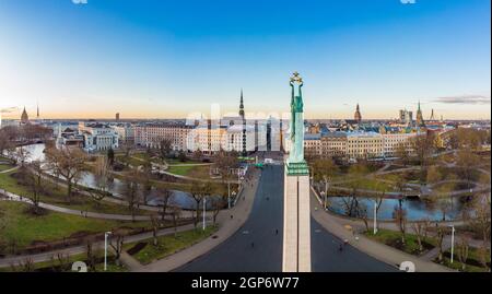 Incredibile vista panoramica aerea del Monumento della libertà con la città vecchia sullo sfondo, durante l'alba d'autunno. Milda - Statua della libertà con tre Golde Foto Stock