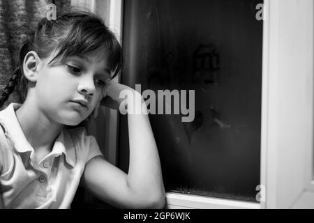 La ragazza disegna figure di piccoli uomini su una finestra appannata Foto Stock