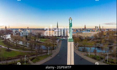 Incredibile vista panoramica aerea del Monumento della libertà con la città vecchia sullo sfondo, durante l'alba d'autunno. Milda - Statua della libertà con tre Golde Foto Stock