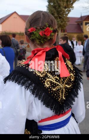 Ragazza vestita in costumi folcloristici andare in chiesa durante la Santa Messa il giorno del Ringraziamento in Stitar, Croazia Foto Stock