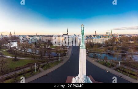 Incredibile vista panoramica aerea del Monumento della libertà con la città vecchia sullo sfondo, durante l'alba d'autunno. Milda - Statua della libertà con tre Golde Foto Stock