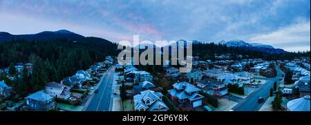 Vista panoramica aerea delle case residenziali in una città turistica. Cielo Sunrise colorato. Preso in Squamish, a nord di Vancouver, British Columbia, Canada. Foto Stock