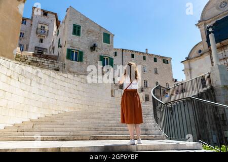 Sibenik, Croazia-4 giugno 2021: Turista femminile che scatta foto al meraviglioso, vecchio, sito patrimonio mondiale dell'UNESCO di Sibenik e la sua bella pietra hou Foto Stock