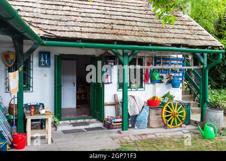 Particolare di casetta rurale cortile interno con attrezzatura colorata per il giardinaggio in portico in legno, Budakalasz, Ungheria Foto Stock