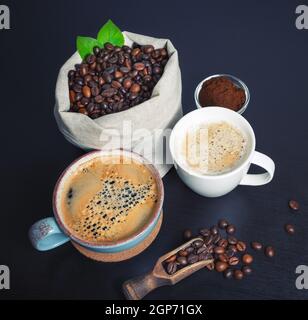 Delizioso caffè fresco. Tazze di caffè, chicchi di caffè tostati in sacco di tela e polvere macinata. Foto Stock