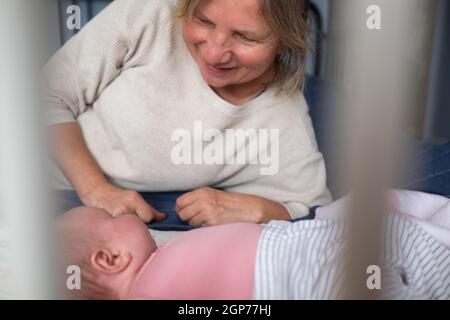 Nonna anziana che tiene un neonato tra le braccia Foto Stock