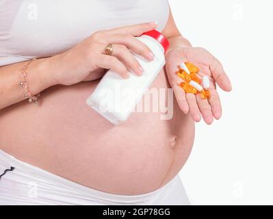 Una donna incinta con le pillole in mano Foto Stock