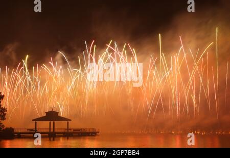 Fuochi d'artificio al Delco Park. Molo di pesca e la silhouette del padiglione in primo piano dei fuochi d'artificio esposti al suolo. Delco Park, Kettering, Dayton, Ohio, Stati Uniti. Foto Stock
