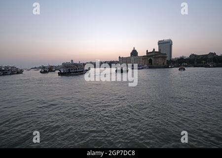 Taj Mahal Hotel, Gateway of India e barche turistiche in acqua del Mar Arabico al tramonto a Mumbai, India Foto Stock