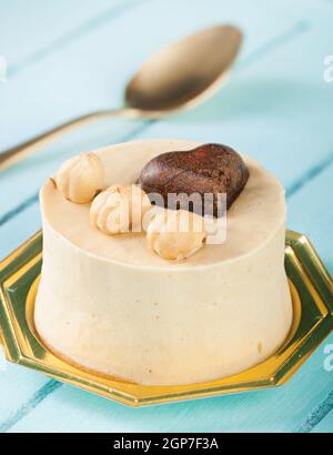 Piccola torta di nocciole e cioccolato fondente cuore blu sul tavolo di legno. Foto Stock