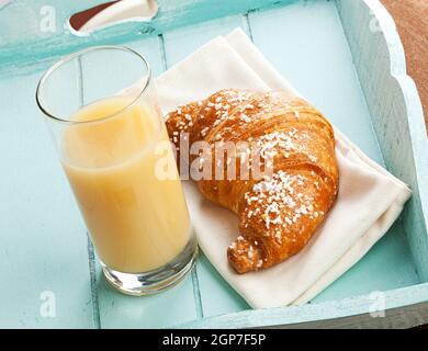 Croissant e succhi di pera sulla luce blu vassoio. Foto Stock