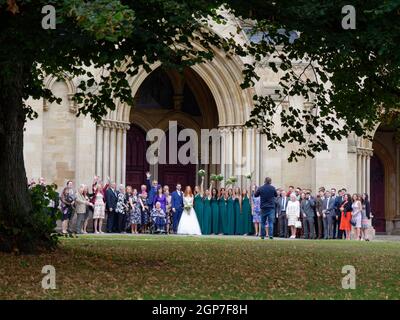 St Albans, Hertfordshire, Inghilterra, settembre 21 2021: Matrimonio autunnale di fronte alla Cattedrale come le bridesmaids tenere bouquet in aria per un pho Foto Stock