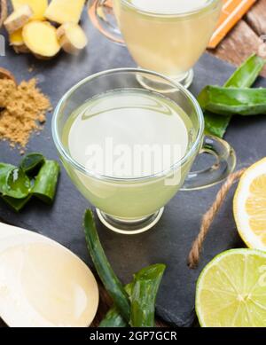 Bere con aloe vera e limoni. Le coppe di vetro su un vassoio di ardesia Foto Stock