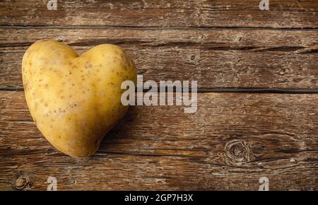 A forma di cuore sulla patata in legno scuro tavolo. Foto Stock