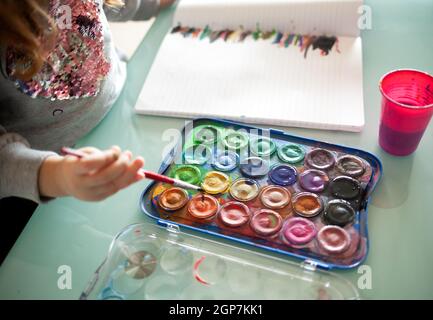 Mani di piccola ragazza pittura con acquerelli a casa. Imparare, istruzione, concetto di infanzia felice. Formazione a distanza durante il periodo di quarantena dovuto Foto Stock