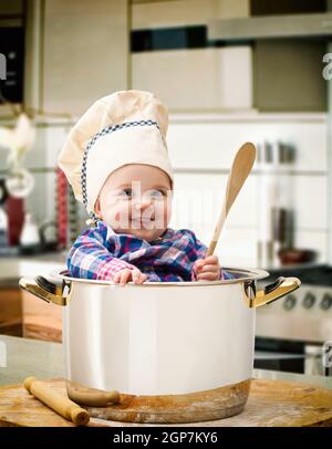 New Born Baby girl Chef in una pentola di acciaio con legno mattarello e cucchiaio. Foto Stock