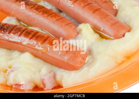 Salsicce con purea di patate nel piatto arancione Foto Stock