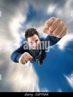 Il supereroe con pugno spinta in avanti volare nel cielo Foto Stock