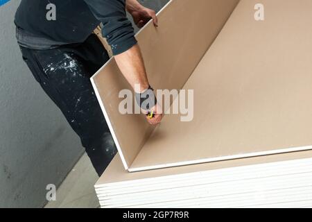 Lavoratore a lavorare per la costruzione di una parete di cartongesso. Foto Stock