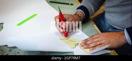 Calzolaio o scarpa designer che lavora con lcon libro modelli per taglio di pelle. Foto Stock