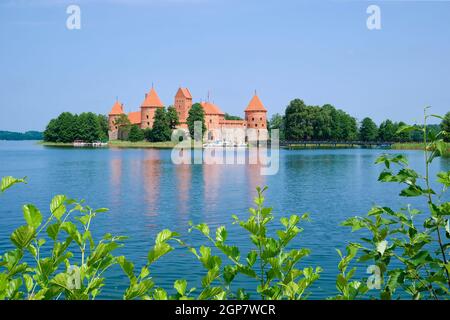 castello d'acqua trakai in una giornata estiva soleggiata, le modifiche verdi sono in primo piano, barche a vela sono situate di fronte alla fortezza Foto Stock