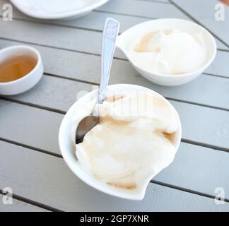 Lo yogurt greco con miele in una pentola posta su un tavolo di legno. Foto Stock