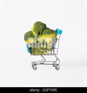 Carrello giocattolo o carrello pieno di broccoli isolato su sfondo bianco. Concetto di vendita del raccolto autunnale. Foto Stock