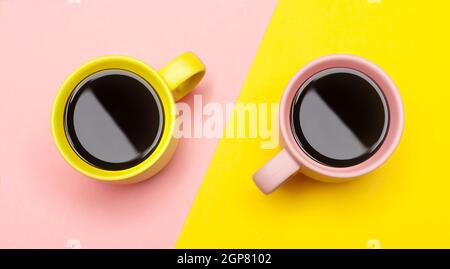 Lay piatto vista dall'alto di due tazze da caffè con rosa e giallo. Foto Stock