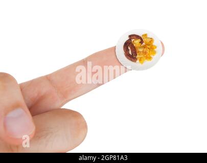 Piatto con salsicce con patate in miniatura sul dito indice. Foto Stock